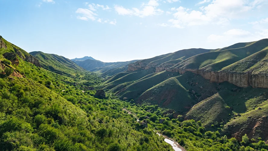 Steep green hills and an unpaved road in the mountains of Kazakhstan